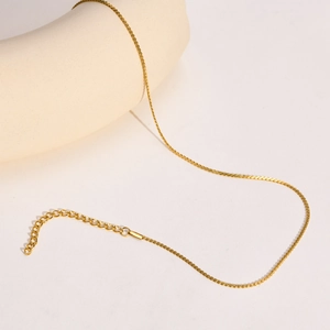 Minimalist 18k gold plated S-shaped chain necklace on a white stone background
