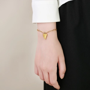Nahaufnahme des minimalistischen goldenen Herzanhänger-Armbands am Handgelenk