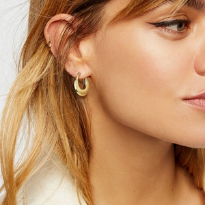 Gros plan de boucles d'oreilles créoles creuses et ear cuffs en or 18 carats