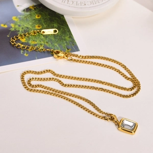 Detail of gold curb chain necklace with square zircon pendant and stainless steel tag