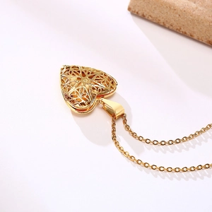 Detail of a golden heart-shaped hollow locket necklace with floral engraved patterns