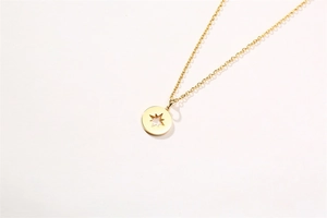 Détail macro du pendentif pièce dorée avec étoile évidée sur chaîne fine