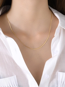 Close-up of elegant 18k gold-plated S-link chain necklace worn over a white linen shirt
