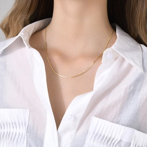 Close-up of a delicate 18k gold-plated S-link chain necklace worn on a female neck