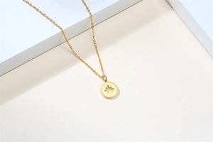 Détail du pendentif médaillon étoile dorée avec bordure texturée et chaîne fine