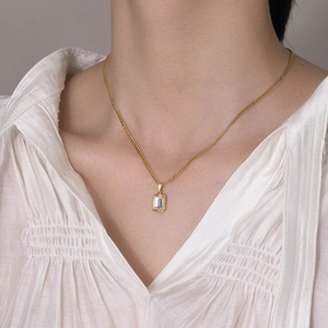 Gold minimalist necklace with rectangular zircon pendant shown on model's neckline