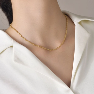 Détail d'une chaîne torsadée en acier inoxydable plaqué or 18k portée par un mannequin