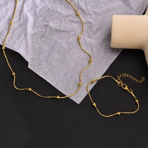 Vue détaillée d'une parure dorée en maille serpent avec perles polies sur fond texturé