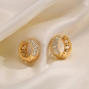 Detail of gold huggie earrings featuring multiple rows of cubic zirconia on silk fabric