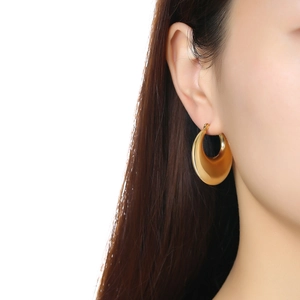 Gros plan de boucles d'oreilles créoles dorées creuses et polies sur un mannequin femme