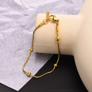 Détail d'un collier chaîne serpent dorée avec cinq perles polies sur un support à bijoux