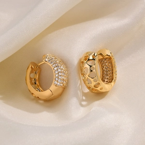 Detail of gold star earrings with pavé zircons and hollow heart pattern on satin