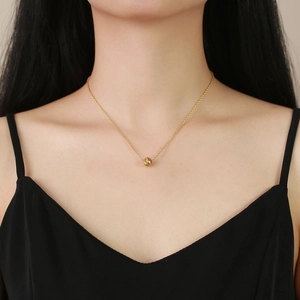 Minimalist gold stainless steel necklace featuring a single textured bead pendant on model