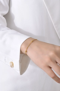 Gros plan d'un bracelet serpent doré avec de petites perles au poignet d'une femme