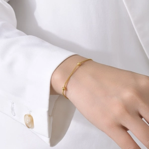 Gros plan d'un bracelet minimaliste en chaîne serpent dorée avec trois perles fines