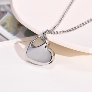 Macro detail of heart-shaped memorial locket pendant showing screw seal and silver finish