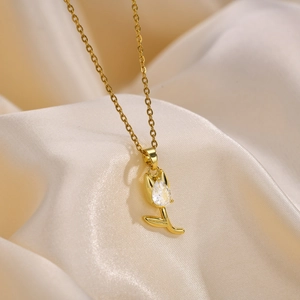 Détail du collier tulipe dorée avec zircon sur un tissu de soie beige très élégant