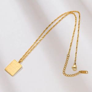 Detailed macro view of 18K gold checkerboard pendant necklace with lobster clasp and chain