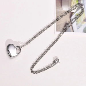 Macro detail of silver heart urn pendant with Forever In My Heart engraved text