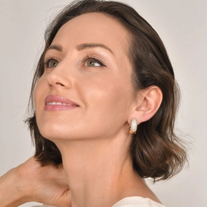 Close-up of elegant gold four-pointed star earrings with paved zircon on model