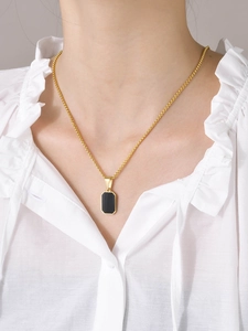 Detail einer minimalistischen Goldkette mit schwarzem Rechteck-Anhänger am Model