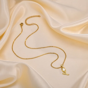 Détail du pendentif tulipe doré avec zircon rouge sur un fond de tissu en soie
