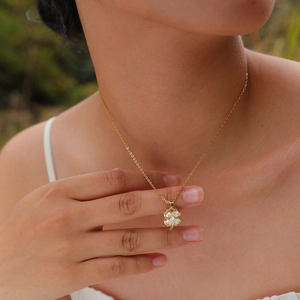 Dettaglio della collana a quadrifoglio dorata con zirconi indossata da una modella
