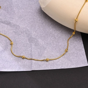 Détail d'un collier chaîne serpent dorée en acier inoxydable avec petites perles