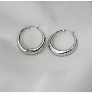 Détail de boucles d'oreilles créoles épaisses argentées au fini miroir poli
