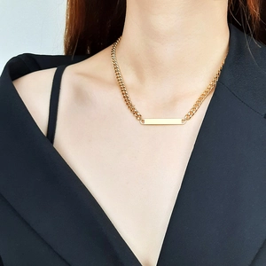 Close-up of a 18K gold-plated chunky bar necklace worn on a female model with black suit