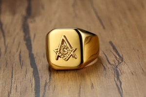 Macro shot of gold stainless steel Freemason ring with engraved square and compass symbol