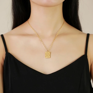 Gold stainless steel checkerboard square pendant necklace on model's neckline