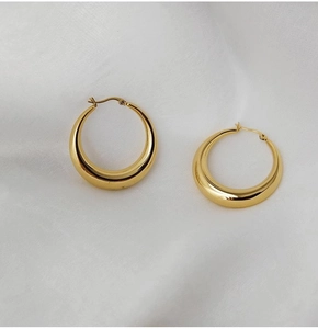 Vue détaillée de créoles creuses en forme de C plaquées or 18 carats sur tissu blanc