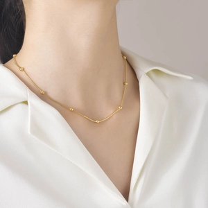 Gros plan d'un collier chaîne serpent dorée en acier inoxydable avec de petites perles