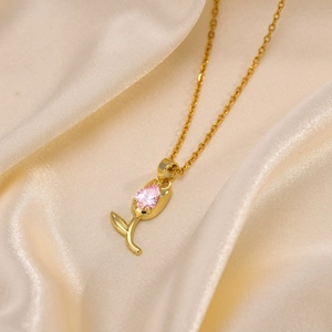 Détail du collier tulipe doré avec zircon rose en forme de goutte sur du satin
