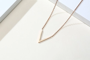 Vue détaillée du pendentif en V 3D en finition or rose sur une fine chaîne