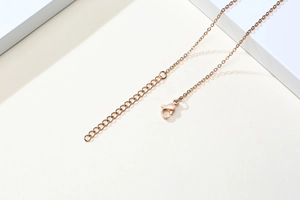 Détail d'une chaîne d'extension en acier inoxydable or rose avec fermoir mousqueton