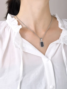 Detail der minimalistischen Edelstahlkette mit schwarzem geometrischem Anhänger am Model