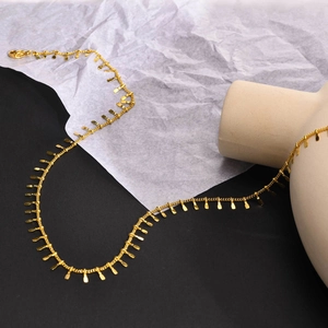 Détail du collier doré en acier inoxydable avec pendentifs plats et fermoir mousqueton