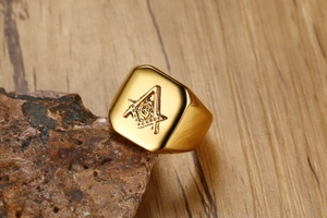 Macro shot of gold stainless steel Masonic ring with square signet on wood background