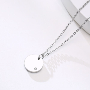 Detail of round gold stainless steel pendant featuring a sparkling cubic zirconia inlay