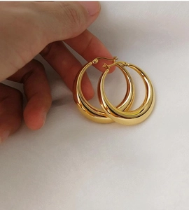 Vue détaillée de boucles d'oreilles créoles épaisses en or 18 carats avec fini poli