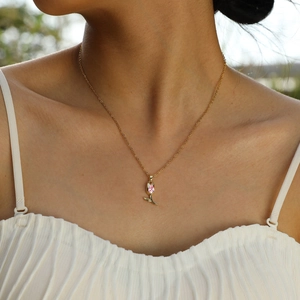 Collier doré avec pendentif tulipe rose et pierre zircon sur cou de femme