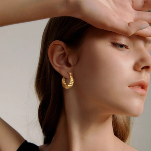 Boucles d'oreilles créoles croissant dorées avec texture métallique torsadée sur mannequin