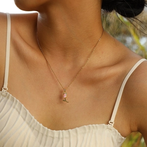 Gros plan du collier tulipe doré avec zircon rose porté au cou d'une femme