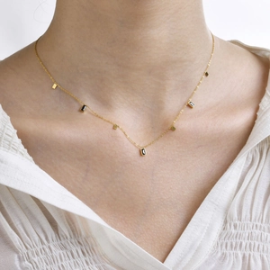 Detail of gold necklace with rectangular black zircon charms worn on neck