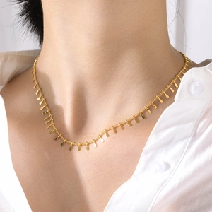 Vue détaillée d'un collier en acier inoxydable doré porté au cou avec pendentifs