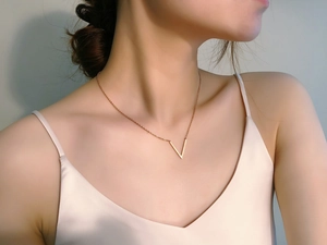 Vue rapprochée d'un collier pendentif en V or rose minimaliste sur un mannequin