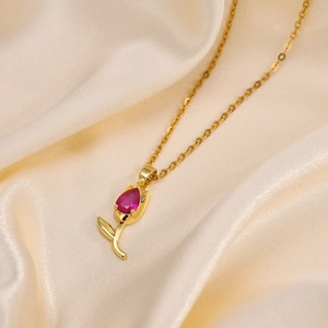 Gros plan du pendentif tulipe doré avec zircon rouge sur fond élégant en soie brillante