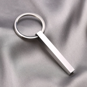 Polished stainless steel rectangular pendant keychain on elegant grey silk background